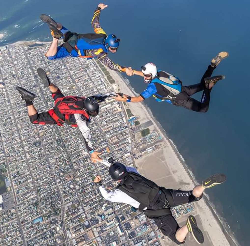 aerial cinematography - skydiving stunts over beach